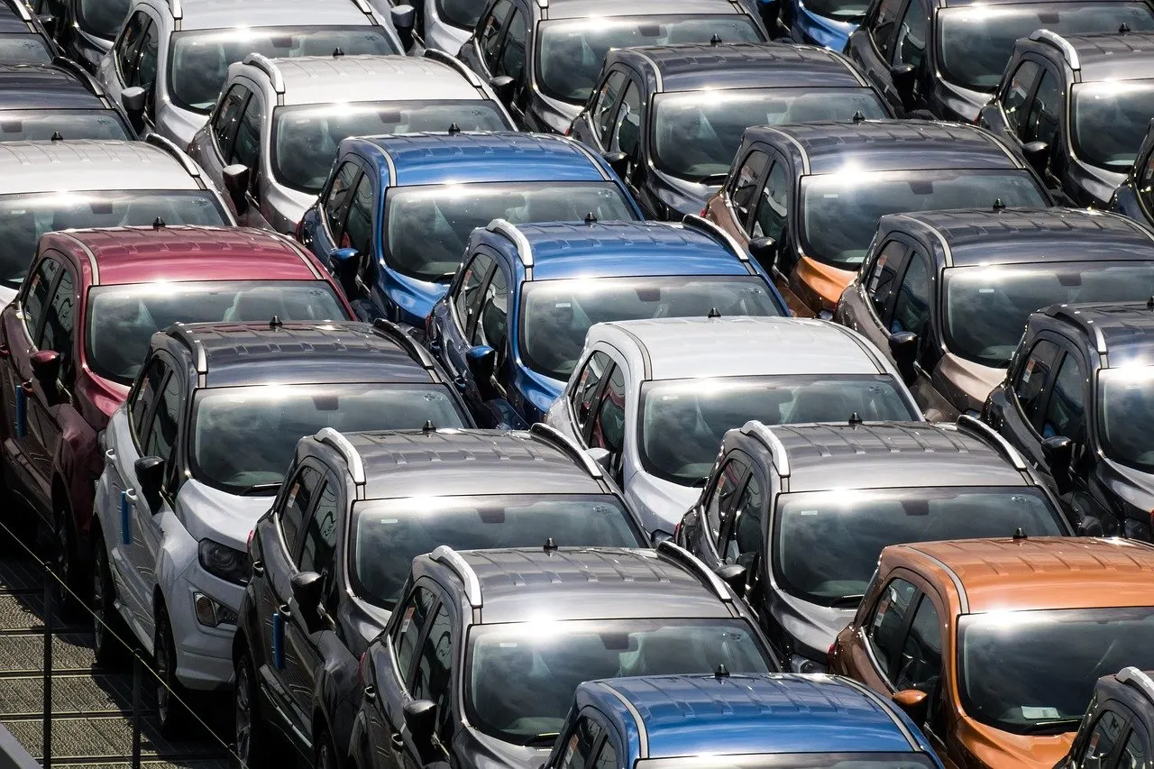 Dicht geparkte Reihen neuer Autos in verschiedenen Farben auf einem Abstellplatz, von schräg oben fotografiert